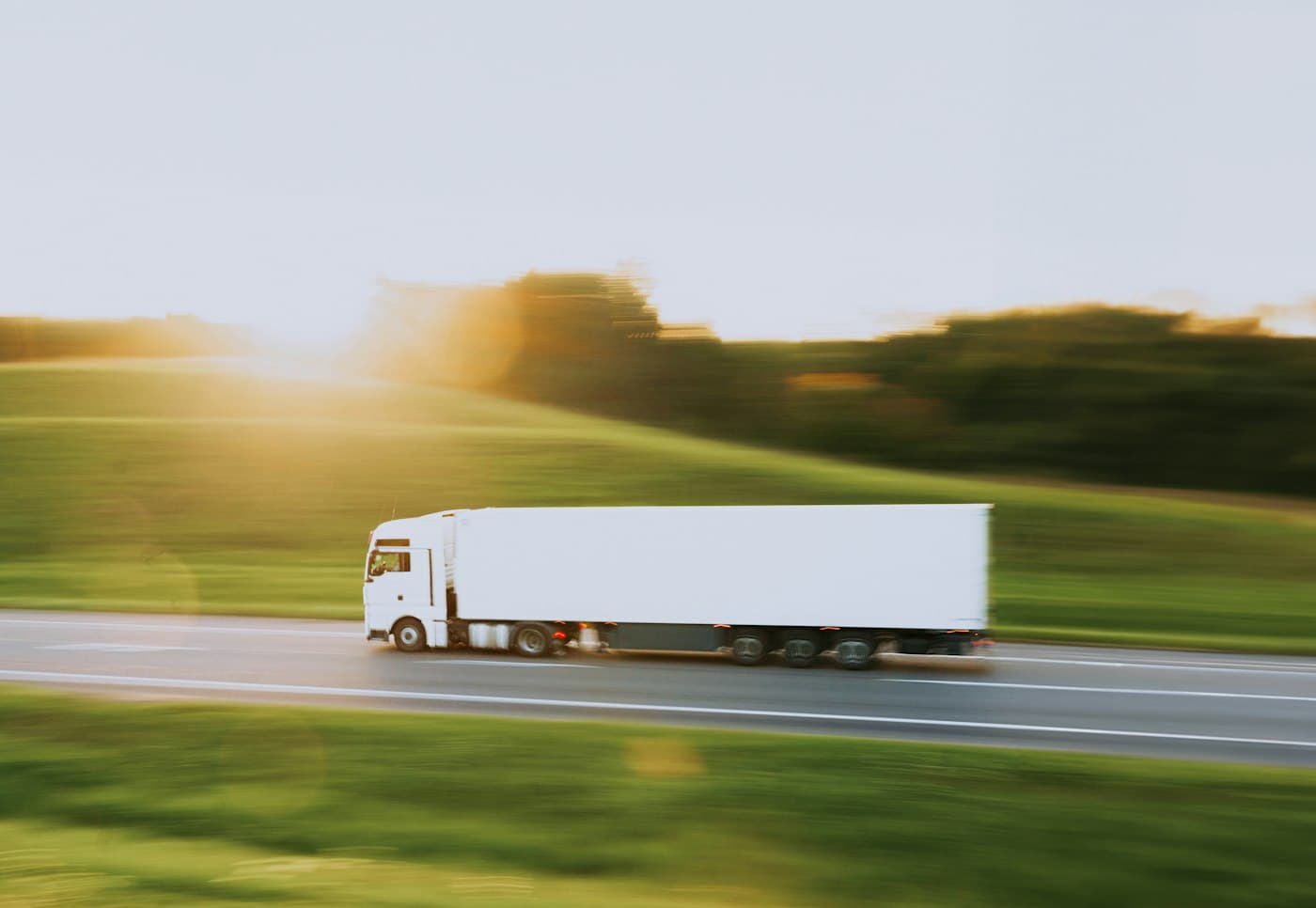 White articulated lorry on a rural road at sunrise