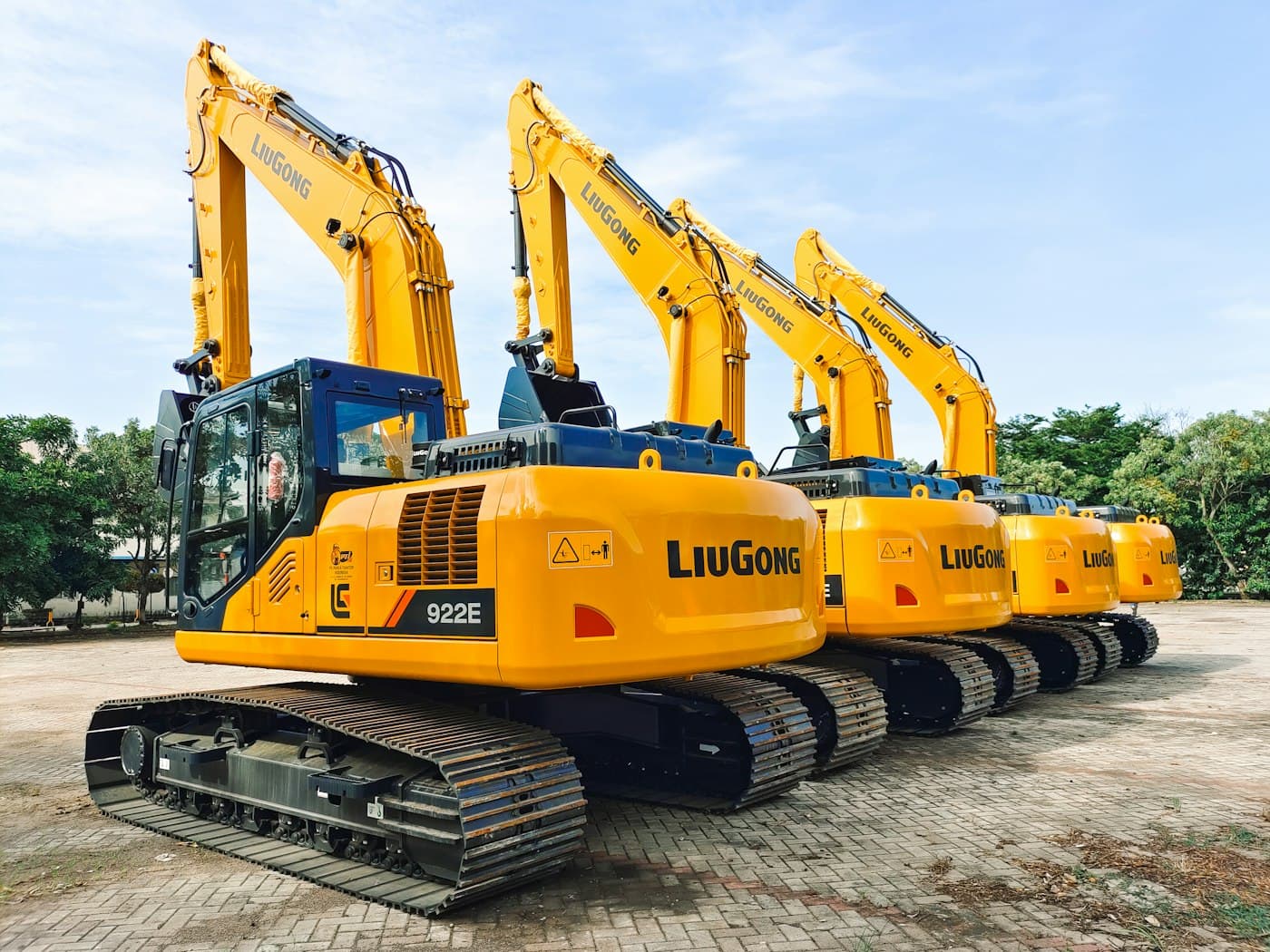 Row of new yellow excavators lined up in a plant yard