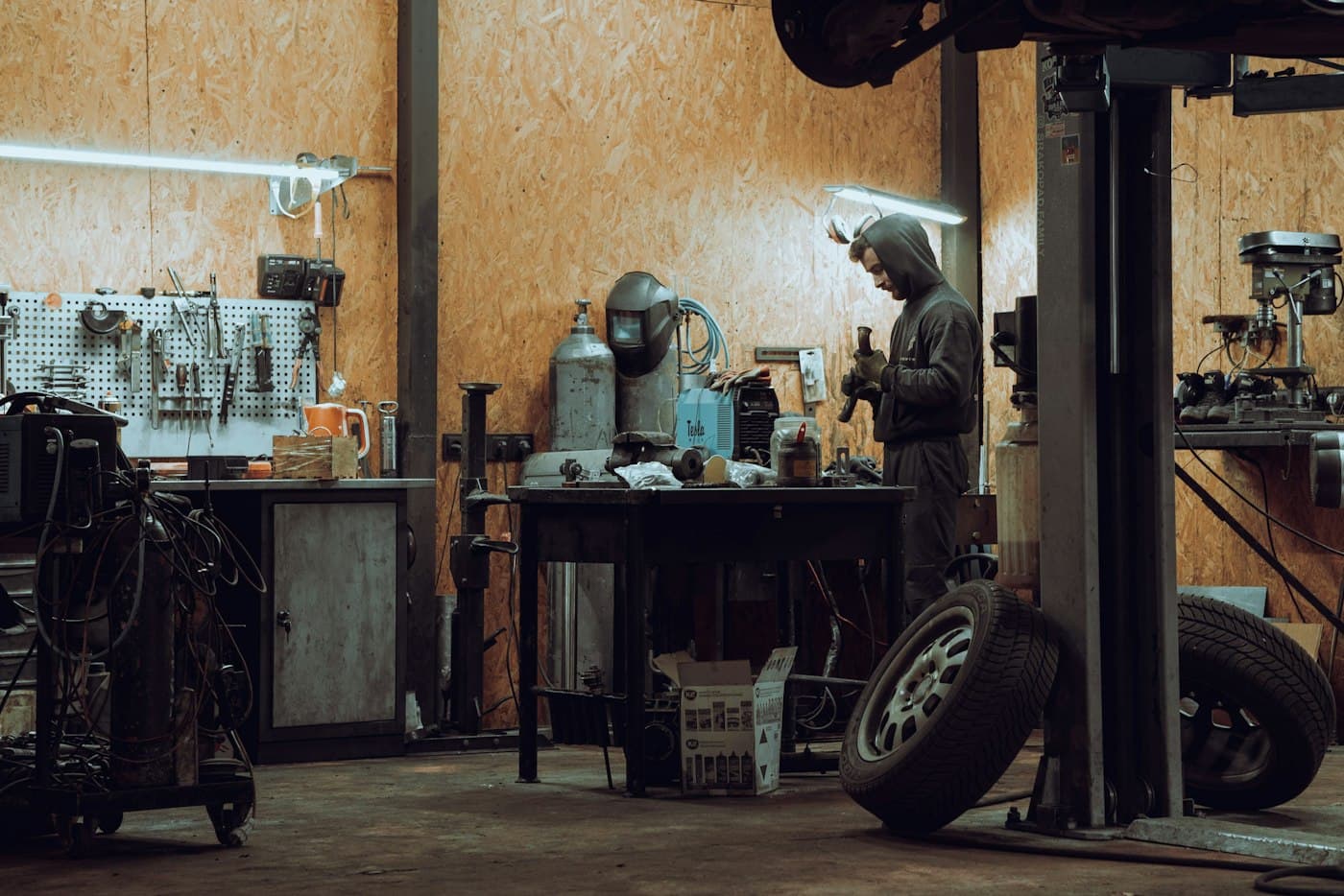 Workshop with pegboard tool wall, workbench, welding kit and a vehicle lift