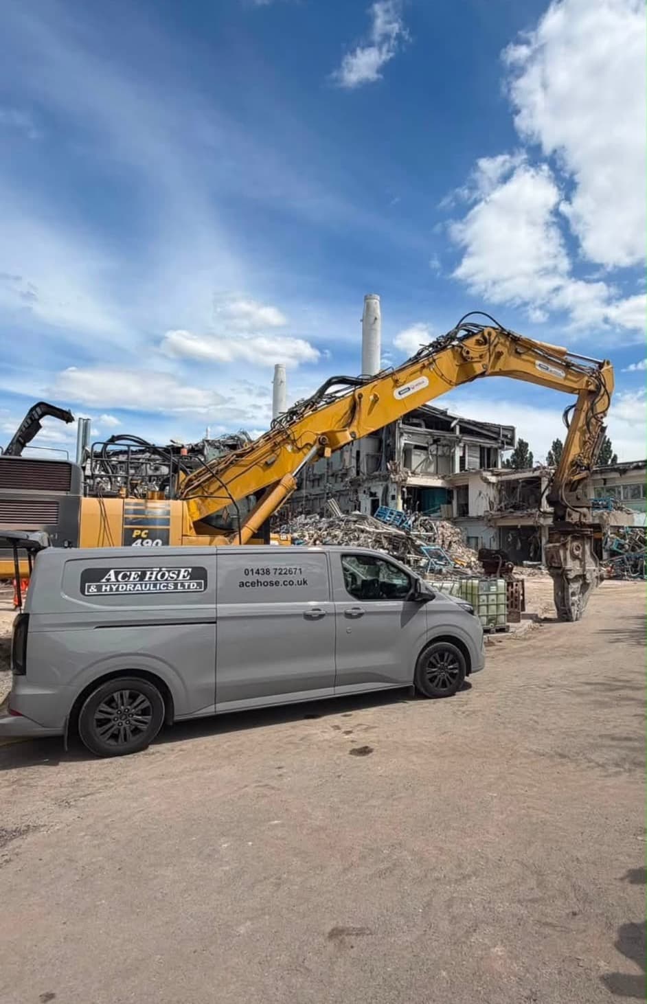 Ace Hose & Hydraulics van on a demolition site beside a yellow long reach excavator